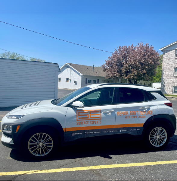 photo of a white car wrapped with the Surface Experts logo with blue sky and a blossoming tree behind it