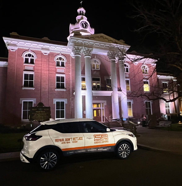 A white car with a Surface Experts logo parked in front of the Murfreesboro, TN Court House at night